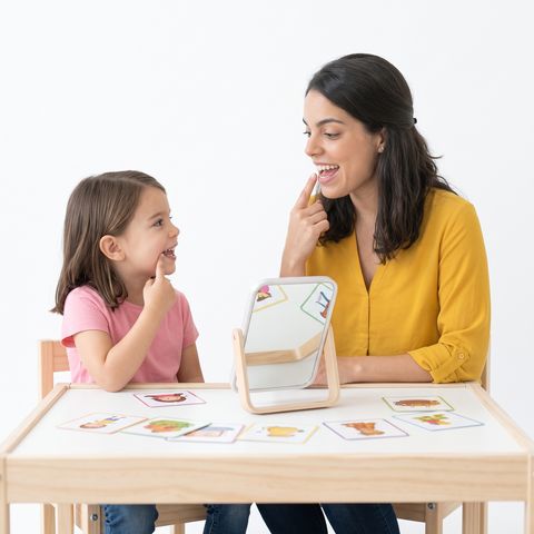 Fonoaudióloga y una niña frente a un espejo trabajando la articulación